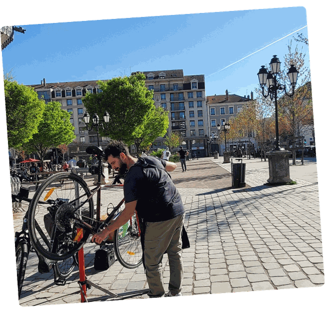 Hugo réparant un vélo sur pied d'atelier sur une place à Lyon
