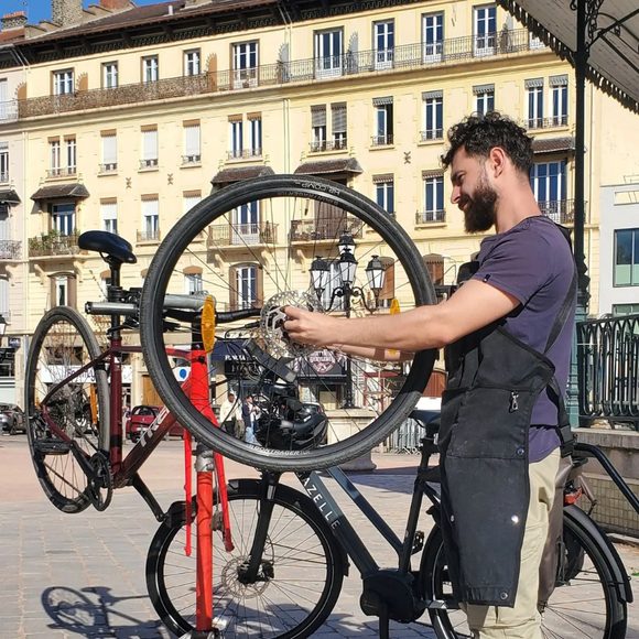 Hugo Parthiot, mécanicien vélo à Lyon, contrôlant une roue de vélo